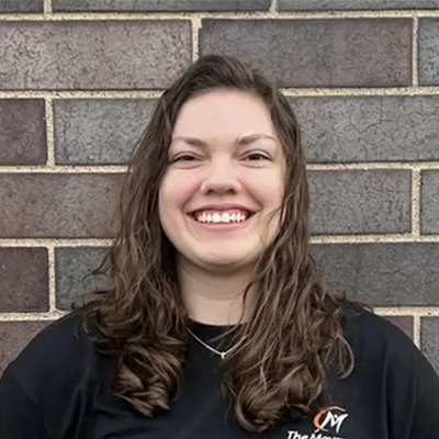 Gabby smiling in front of a brick wall.