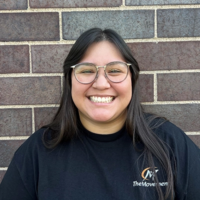Josie smiling in front of a brick wall.