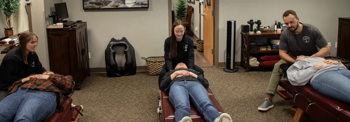 Chiropractor Maple Grove MN Hannah Willford Kevin Jean And Cydney Jean With Patients Chiropractors Hannah Willford, Kevin Jean, And Cydney Jean adjusting patients.