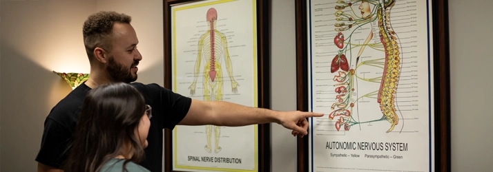 Kevin Jean showing a patient a poster on the autonomic nervous system.